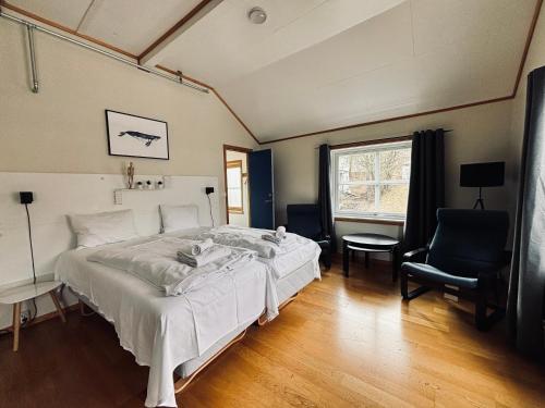 a bedroom with a bed and a chair and a window at Lødingen Brygge in Lødingen