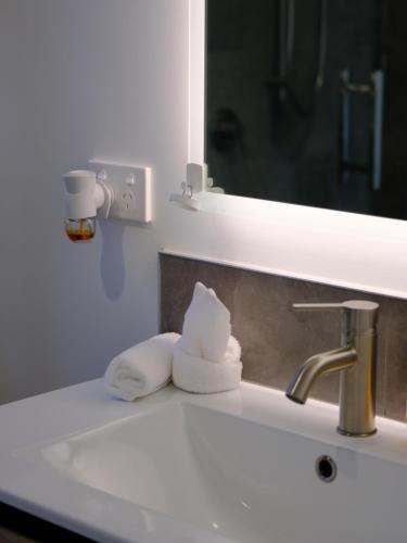 a bathroom sink with a mirror and towels on it at Private Cozy Sleepout with Free Parking & Self Check-in in Hamilton