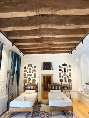 two beds in a room with a wooden ceiling at Barlos Boutique XVIII in Bukhara