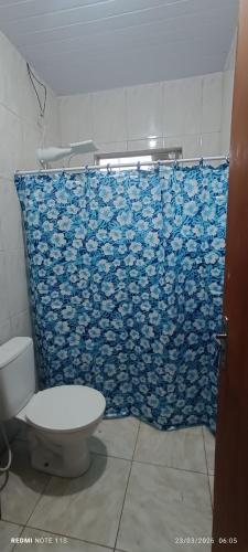 a bathroom with a toilet and a blue shower curtain at Casa amarela in Gonçalves