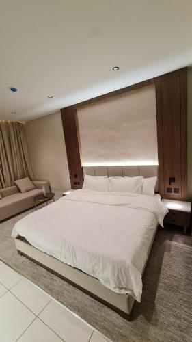 a bedroom with a large white bed and a couch at شقق ضيافة خاصه خدمة ذاتية in Buraydah