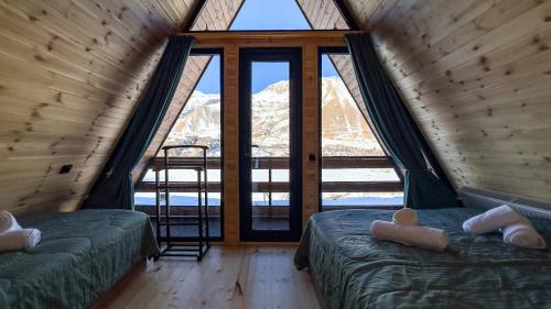 two beds in a room with a large window at Eastlight Cottage in Gorists'ikhe