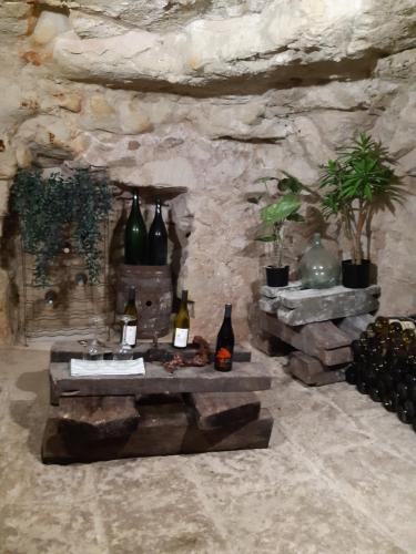 a stone room with a table with bottles on it at TROGLODYTE - La Grotte d'Auré in Le Puy-Notre-Dame
