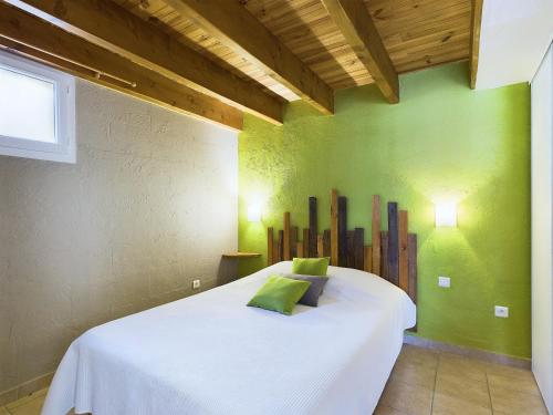 a bedroom with a white bed with a green wall at Gîtes de l'Esquirou in Lagorce
