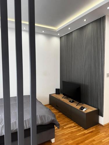 a bedroom with a bed and a flat screen tv at Lux Apartman Inđija in Inđija