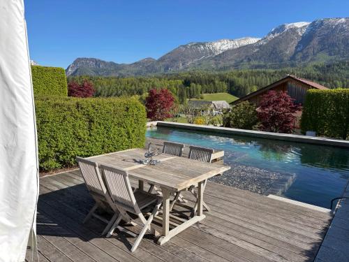 a wooden table and chairs on a deck next to a pool at PurPlus Lodge in Vorderstoder