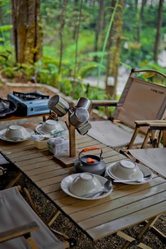 a wooden table with plates and lights on it at serlok glamping in Tangkubanperahu