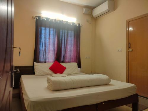 a bed in a room with a red window at MVTJ Hotel in Bangalore