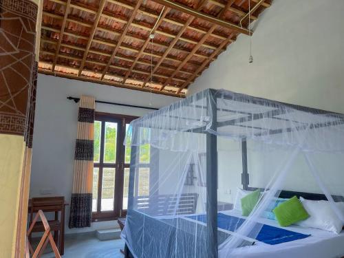 a bedroom with a bed with a mosquito net at Home in the Island in Tangalle