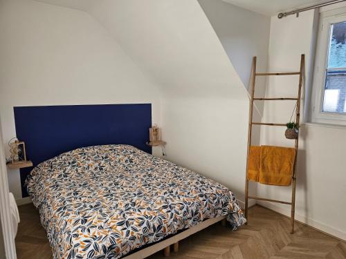 a bedroom with a bed with a blue headboard and a ladder at Cosy travels in Les Andelys