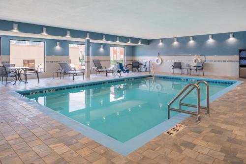 a large swimming pool with tables and chairs in a building at Holiday Inn Express Hotel & Suites Bismarck by IHG in Bismarck