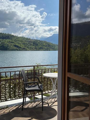 a table and a chair on a balcony with a view of a lake at Albergo Mezzolago in Calceranica al Lago