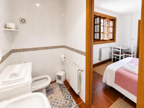 a bathroom with a toilet and a bed in a room at Posada Adela in Santillana del Mar