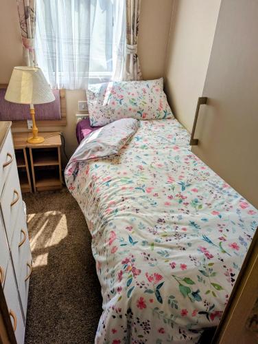 a small bedroom with a bed with a floral comforter at Island Butterfly haven in Sandown