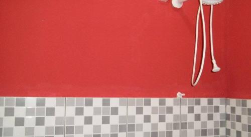 a bathroom with a red wall and a shower at Pousada Del Rio (Santa Rita De Cassia) in Carolina