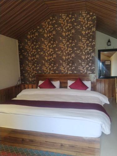 a bedroom with a large bed with red pillows at Shivpur Greens in Mashobra