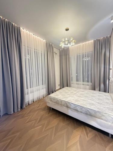 a bedroom with a bed in front of windows at Designer Apartment with Mountain View in Almaty