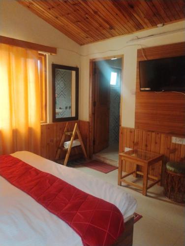 a bedroom with a bed and a flat screen tv at Shivpur Greens in Mashobra