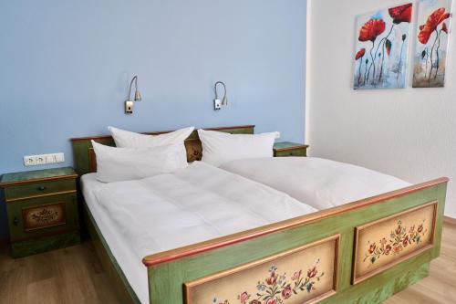 a bedroom with a large bed with white sheets at Hotel Heidenauer Hof in Heidenau