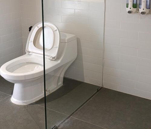 a bathroom with a toilet and a glass shower at Cozzy Bitu Garden in Bunder