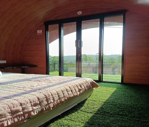 a bedroom with a bed and large glass windows at Cozzy Bitu Garden in Bunder
