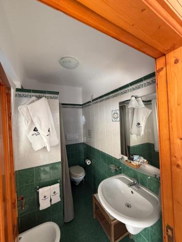 ein grünes Badezimmer mit Waschbecken und Toilette in der Unterkunft Hotel Tesoriero in Panarea