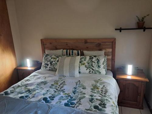 ein Bett in einem Schlafzimmer mit zwei Nachttischen und zwei Kerzen. in der Unterkunft Coco 's Hamlet Flatlet in Prince Alfreds Hamlet