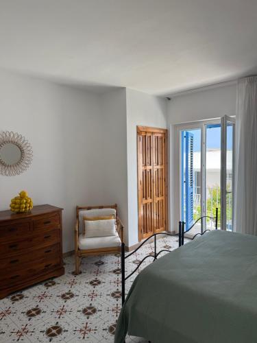 ein Schlafzimmer mit einem Bett und einem Stuhl und Glasschiebetüren in der Unterkunft Hotel Tesoriero in Panarea