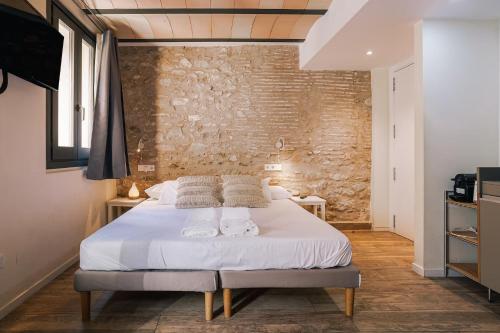 a bed in a room with a brick wall at Aromatik apartments in Girona