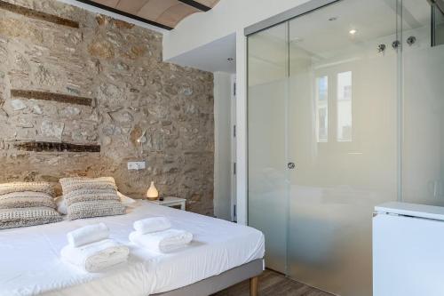 a bedroom with a white bed and a stone wall at Aromatik apartments in Girona
