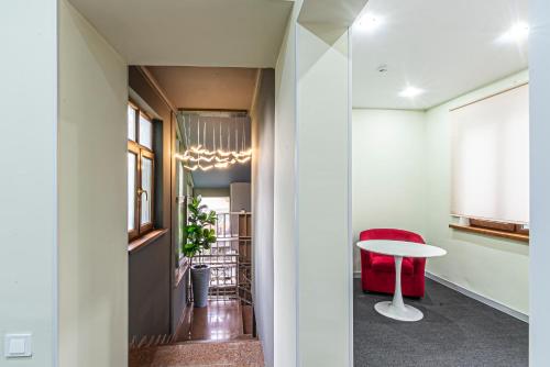 a hallway with a table and a red chair at AYKUN Hotel in Almaty