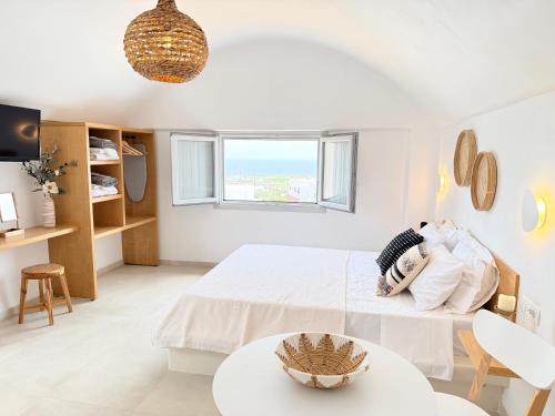 a white bedroom with a bed and a table at Nohēme Luxury Suites in Vourvoúlos