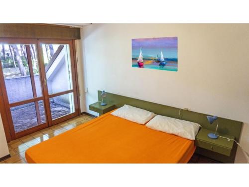 an orange bed in a room with a window at Sotto il Pino 14 in Eraclea Mare