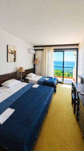 a hotel room with three beds and a large window at CORPUS B - Hotel Albatros in Ulcinj