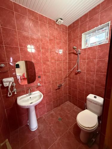 a red tiled bathroom with a toilet and a sink at Hotel Nodmax in Ureki