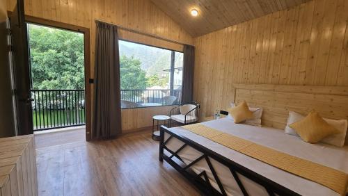 a bedroom with a bed and a large window at Aqua Forest River Resort in Bijni
