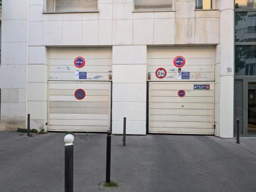 two garage doors on a building with signs on them at Le Jourdain in Paris