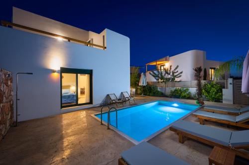 a swimming pool in the backyard of a house at night at Gemini Villas in Theologos