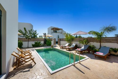 a swimming pool on a patio with chairs and a house at Gemini Villas in Theologos
