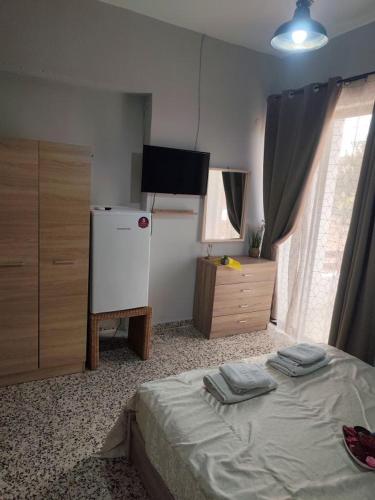 a room with a bed and a refrigerator and a television at Garden studio N4 in Archangelos