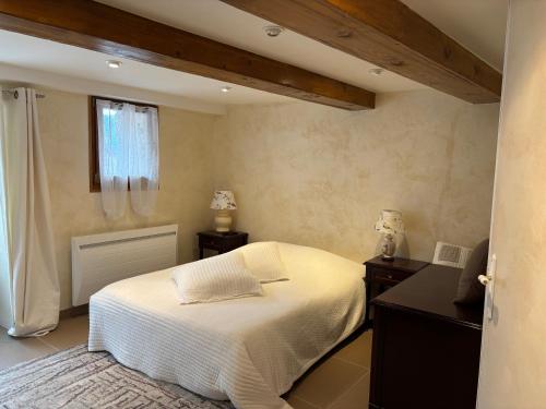 a bedroom with a white bed and a window at La Fenière in Roubion