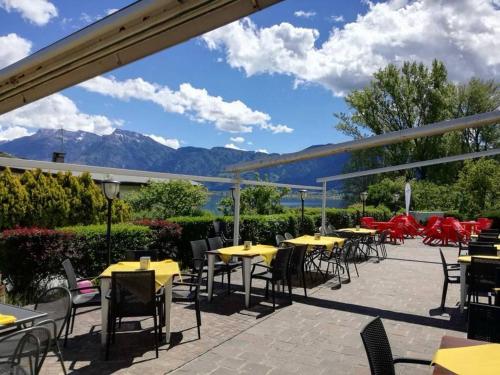 a patio with tables and chairs and mountains in the background at Hotel Mezzolago in Calceranica al Lago