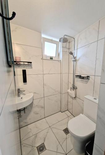 a white bathroom with a toilet and a sink at Xenia Studios in Piskokéfalon