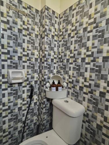 a bathroom with a toilet and a tile wall at Maru Vibe Studio unit in San Juan