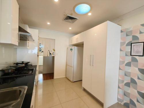 a kitchen with white cabinets and a refrigerator at Bright Double Room N Winston Hills in Toongabbie