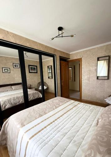 a bedroom with a large white bed and a mirror at Casa Ramona en Foz in Foz