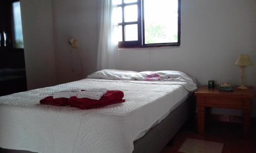 a bedroom with a bed with white sheets and a window at Mini Apartamentos in Neptunia