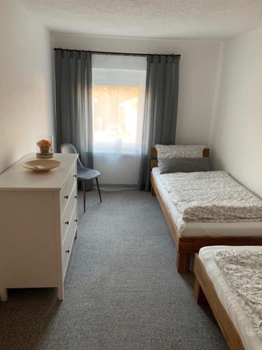 a bedroom with three beds and a desk and a window at Ferienwohnung Gisela in Lohsa
