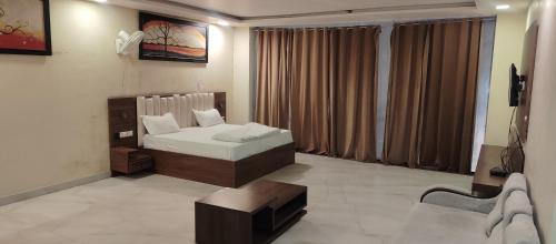 a bedroom with a bed and a bench in it at Hotel Renuka Inn A Unite shyam ganga builders in Deoria