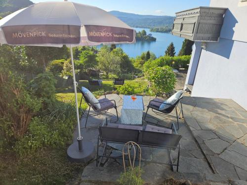 a patio with a table and chairs under an umbrella at Haus Sonnenhang +Seeblick+Pool in Reifnitz